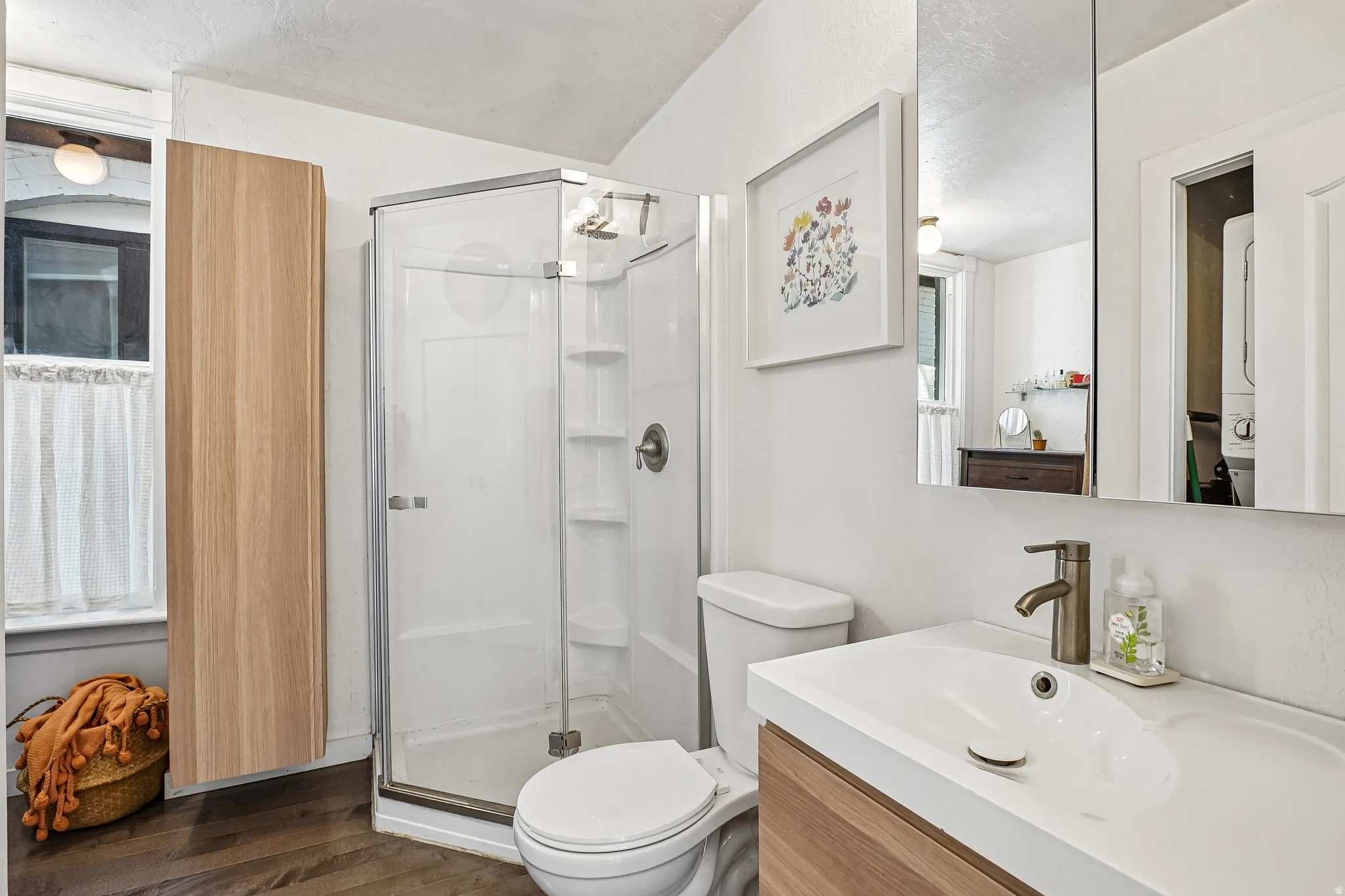 Bathroom featuring a glass-enclosed shower, wood-finish vanity with an integrated sink, and dark wood-finish flooring
