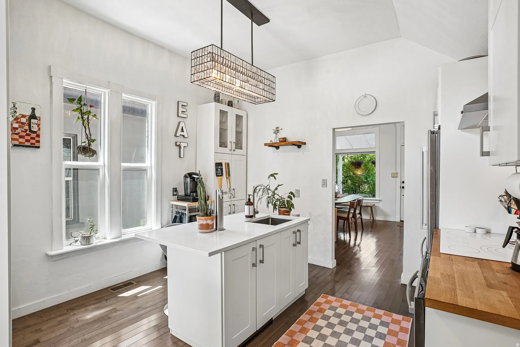 Kitchen featuring a central island with an undermount sink, white cabinetry, and wood-finish flooring