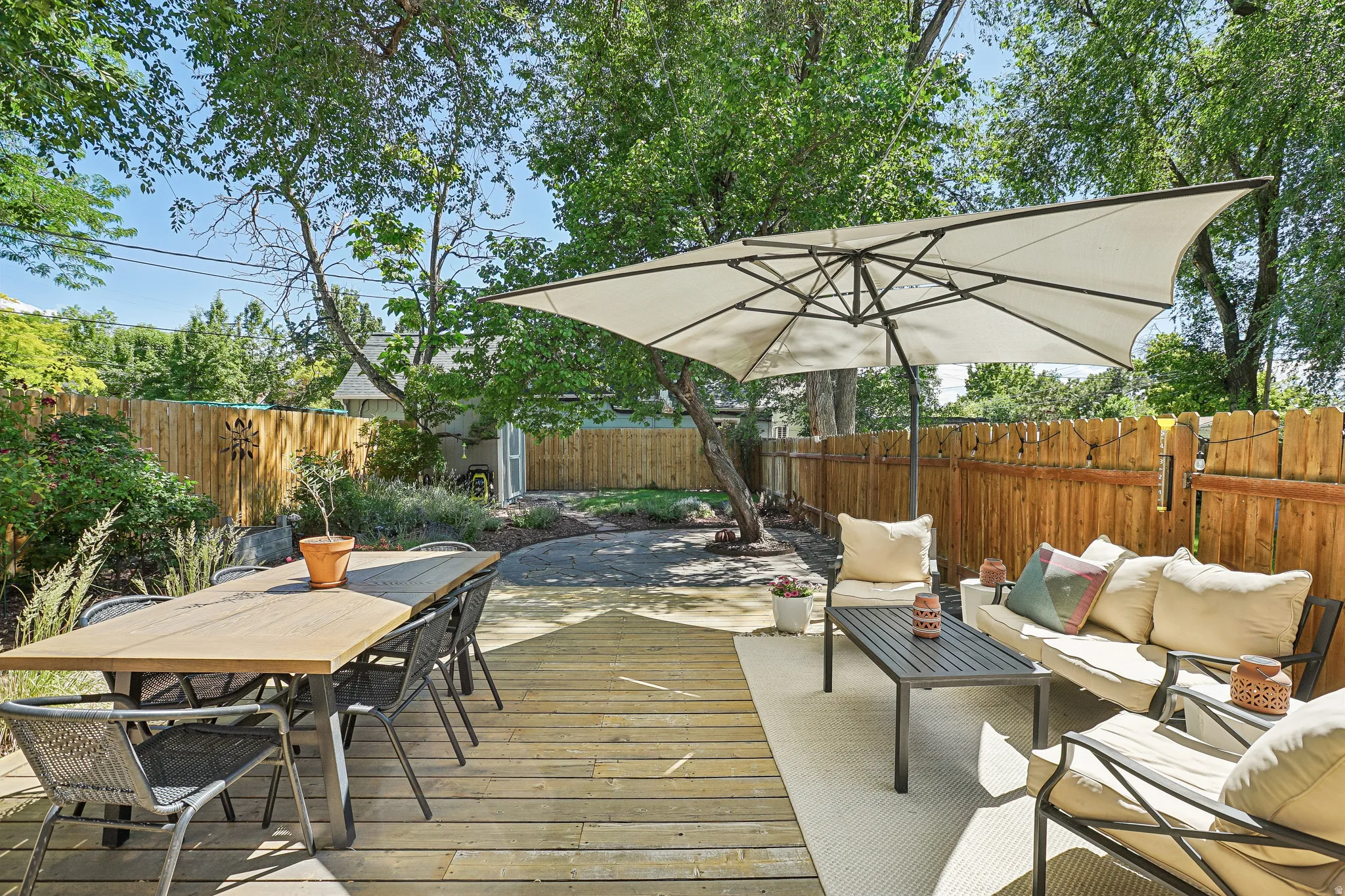 Expansive outdoor decking featuring a dining area, a lounge area, and a large cantilever umbrella