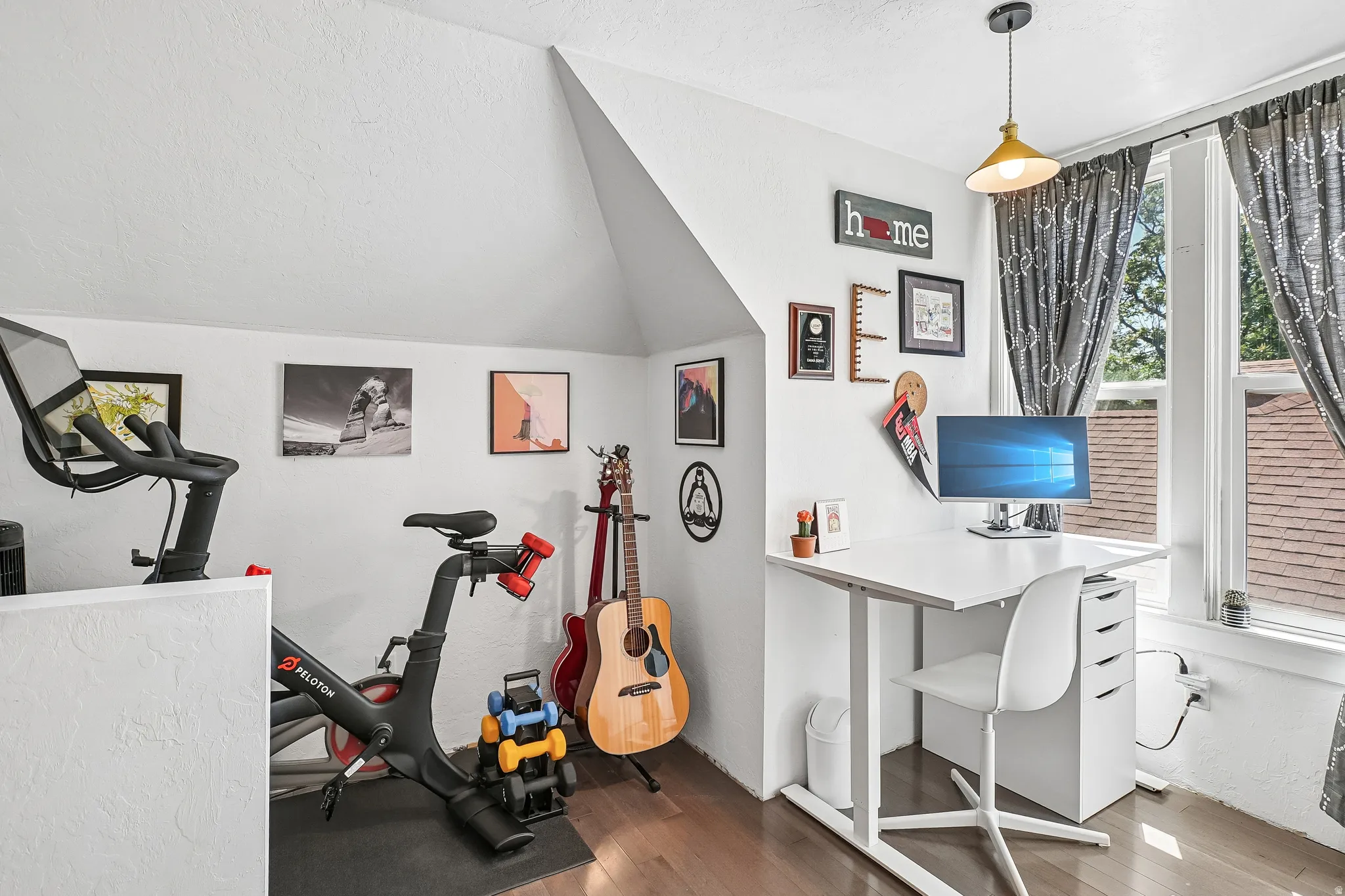 Attic space featuring wood-finish flooring, white walls, and a white ceiling with an angled architectural detail