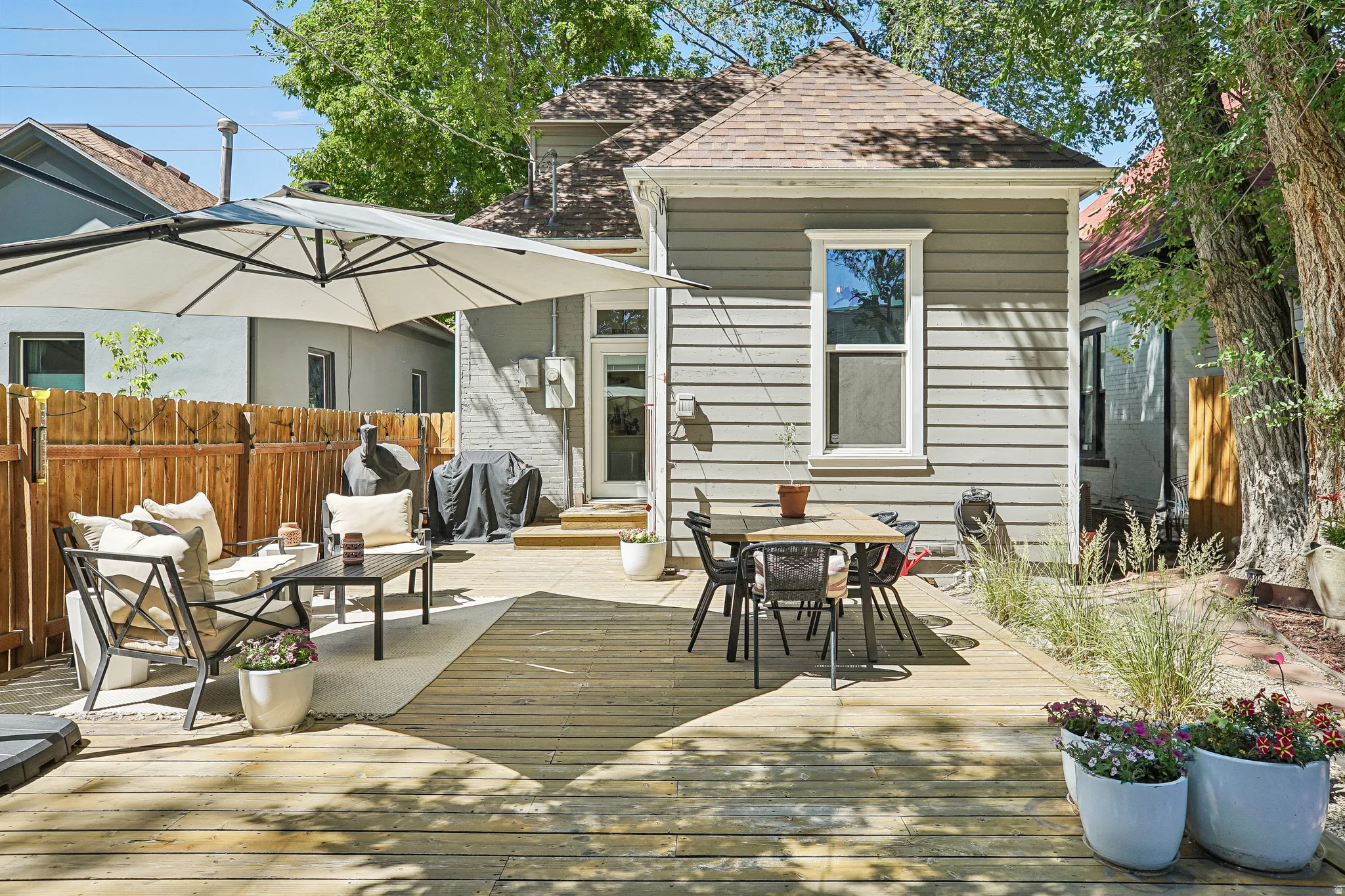 Spacious wood-finish deck with multiple seating areas, a privacy fence, and mature trees