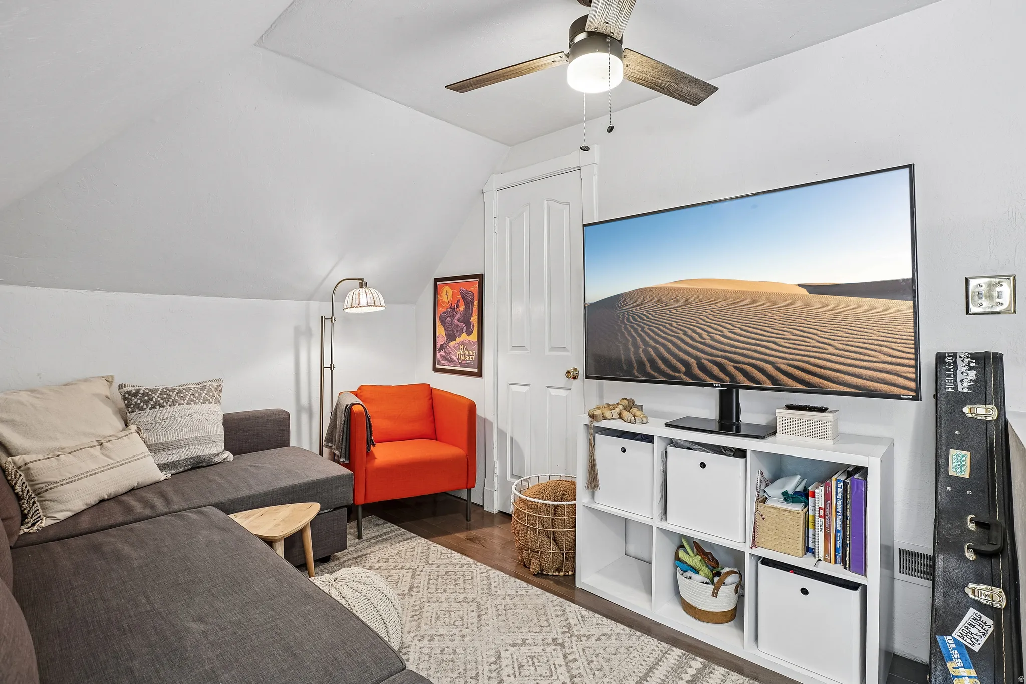 Attic living space featuring sloped ceilings, wood-finish flooring, a ceiling fan, and a built-in storage unit