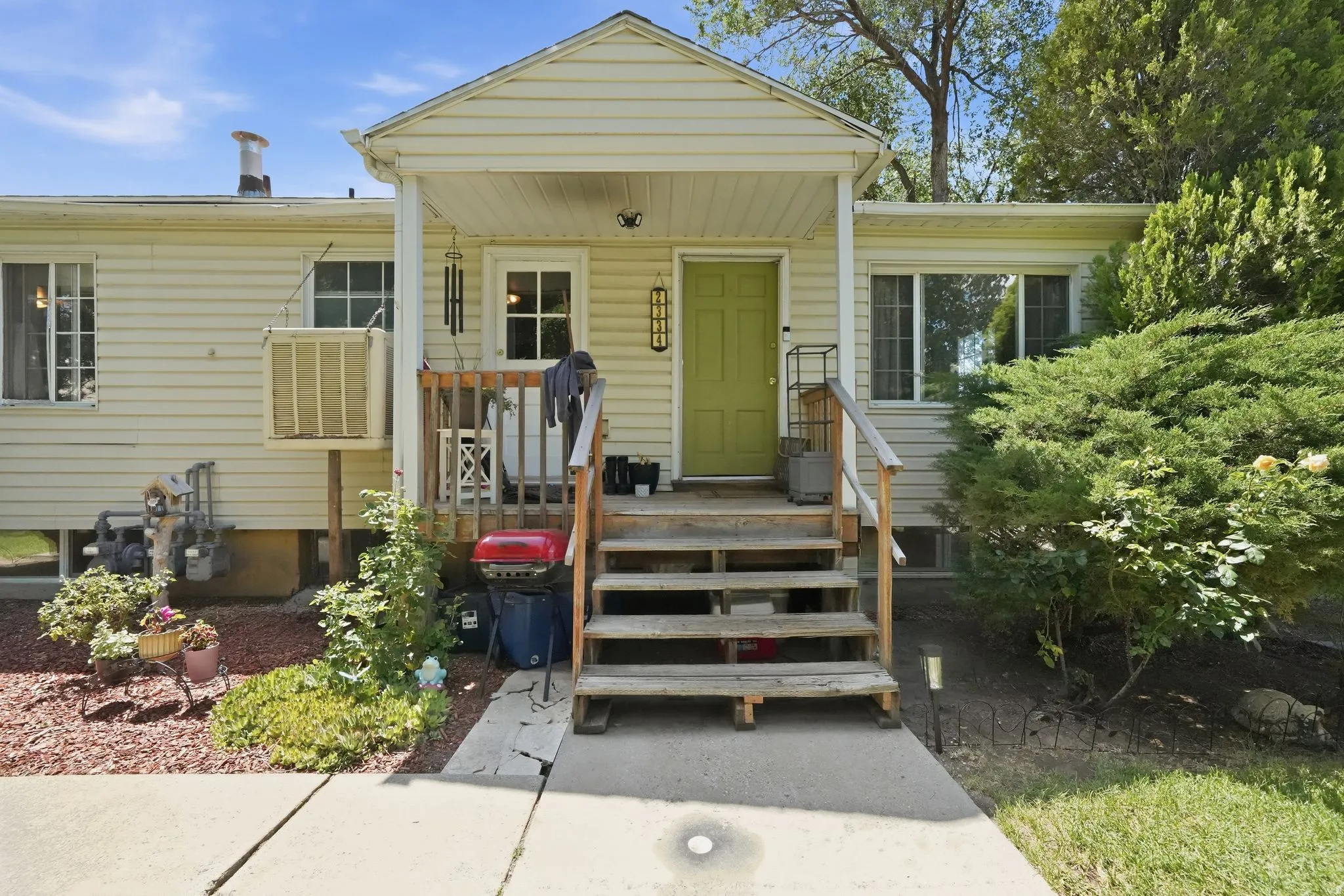 Covered entry with a vibrant green door, durable siding, and mature landscaping