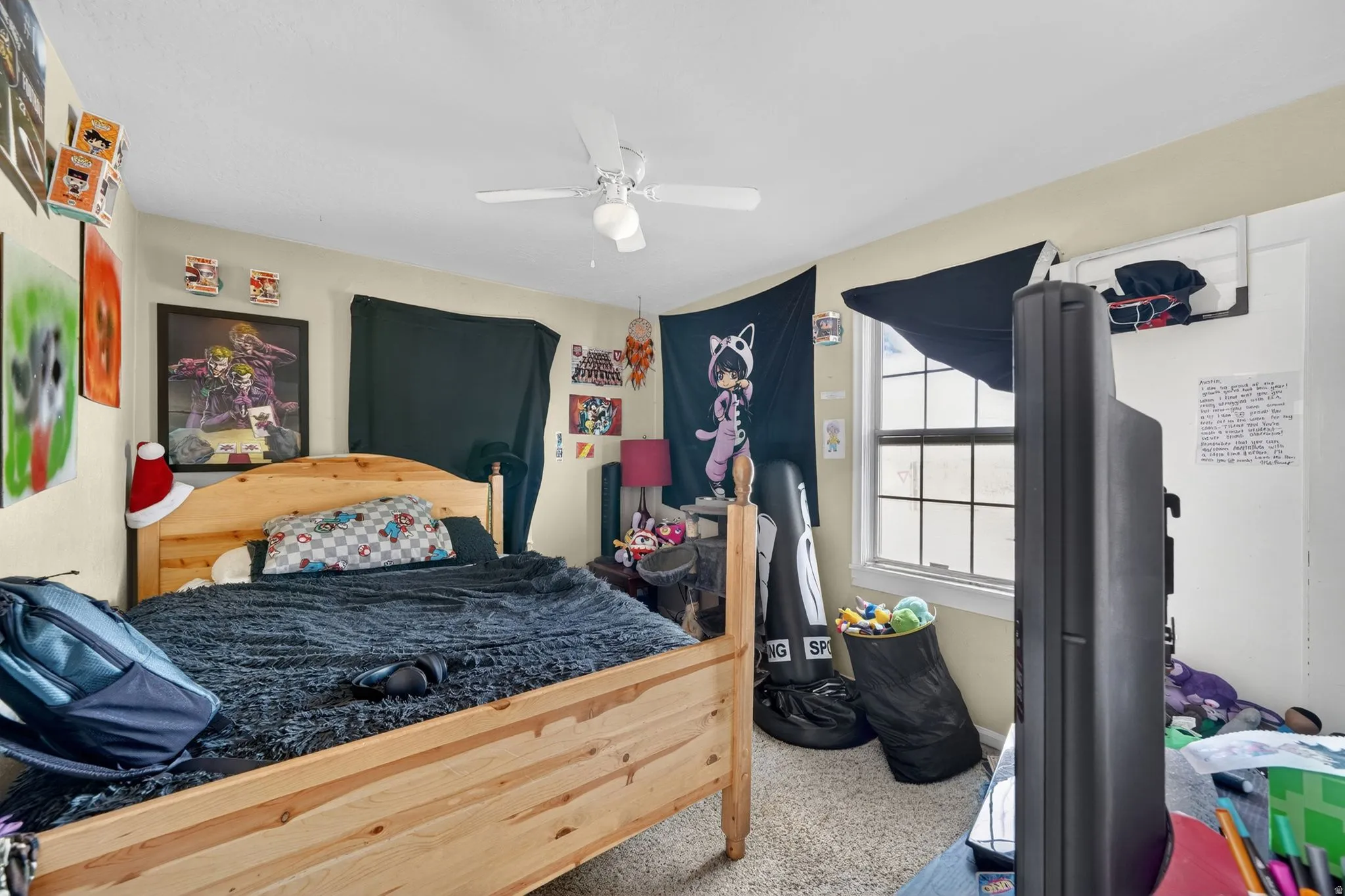 Bedroom featuring a window with natural light, light-colored walls, carpeted flooring, and a ceiling fan