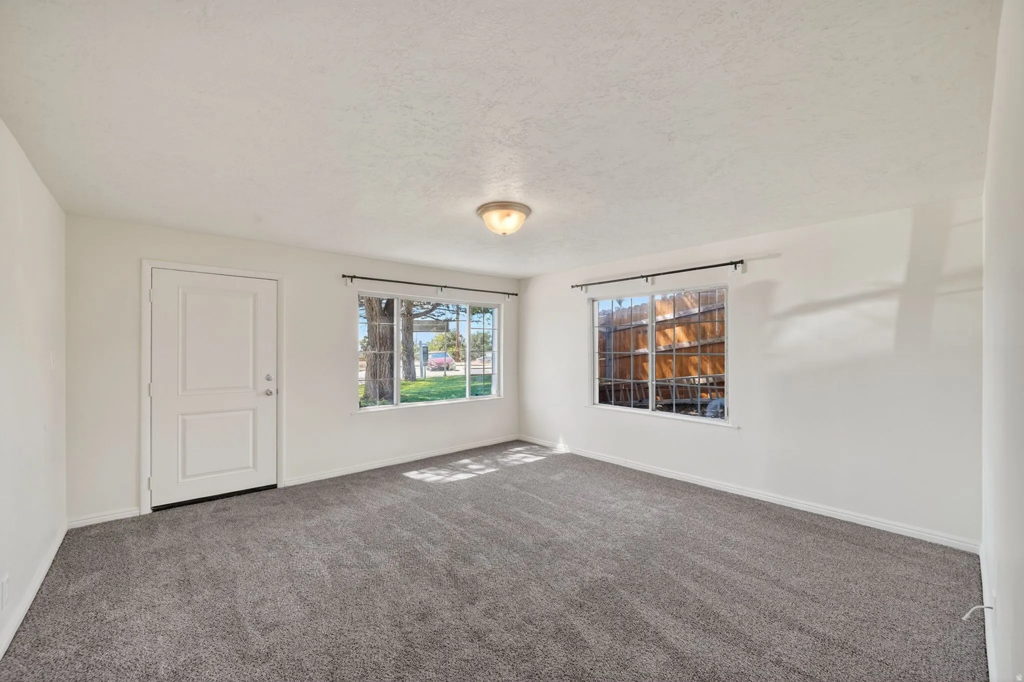 Spacious room featuring neutral carpeting, white walls, and a ceiling-mounted light fixture