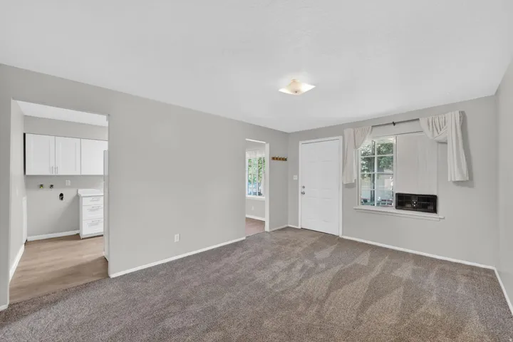 Spacious room featuring gray wall paint, textured carpeting, and a ceiling-mounted light fixture