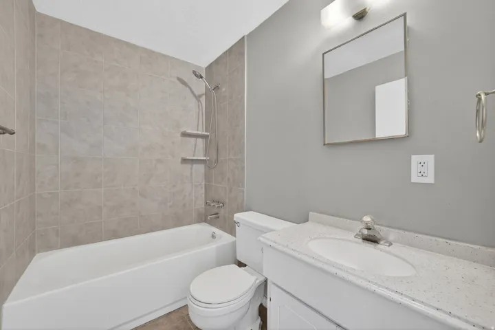 Modern bathroom featuring a white vanity with a speckled countertop, integrated sink, and chrome faucet