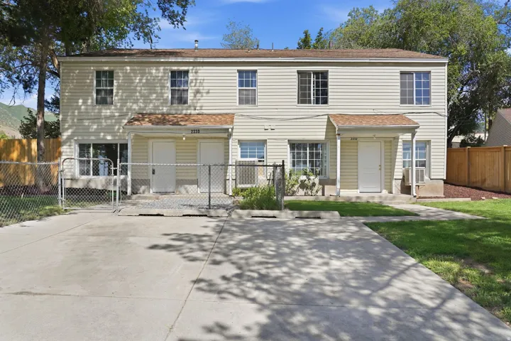 Duplex property featuring light-colored siding and a concrete driveway