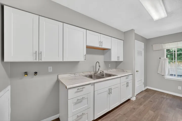 Contemporary white cabinetry with brushed nickel hardware, a stainless steel double sink, and a high-arc faucet