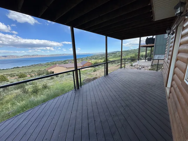 Spacious deck featuring dark composite decking and a cable railing system, offering panoramic water and mountain scenery