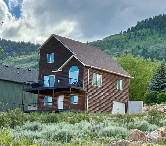 Log-sided residence featuring a multi-level deck and an arched window on the upper level