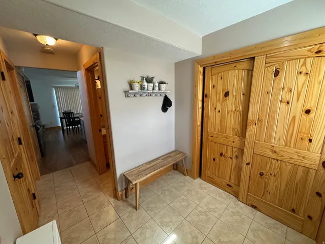 Entryway featuring light-toned tile flooring, natural wood-finish doors, and a built-in closet with sliding doors