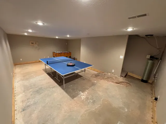 Spacious lower-level room featuring light-toned walls and recessed ceiling lighting