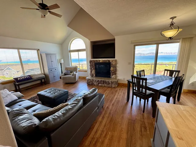Spacious living area featuring wood-finish flooring, a stone-faced fireplace, and high vaulted ceilings