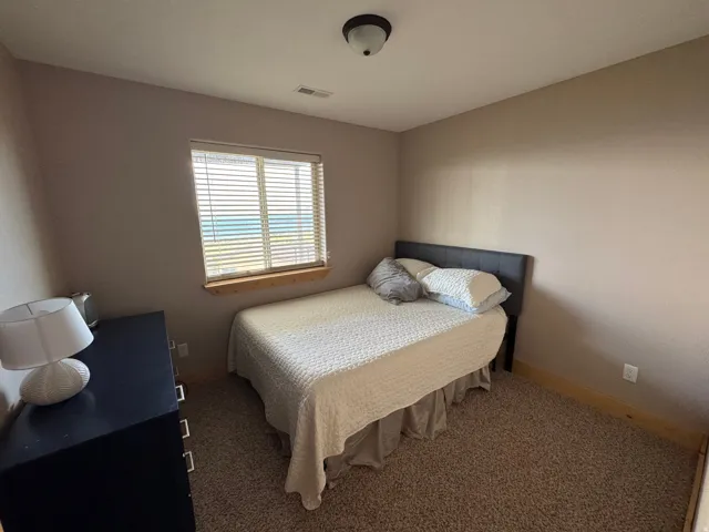 Carpeted room with a window featuring horizontal blinds