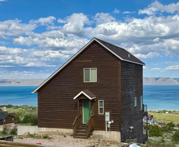 Vertical siding exterior with a pitched roofline, featuring a green entry door with an overhang