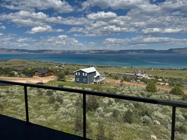 Deck with cable railing system overlooking a large body of water, distant mountains, and scattered residential properties