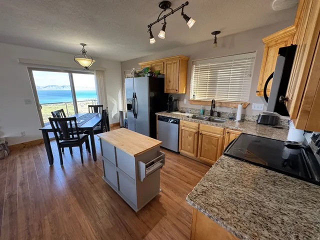 Kitchen featuring wood-finish flooring, granite countertops, and light wood cabinetry