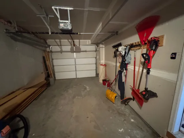 Single-car garage featuring a sectional overhead door and concrete flooring