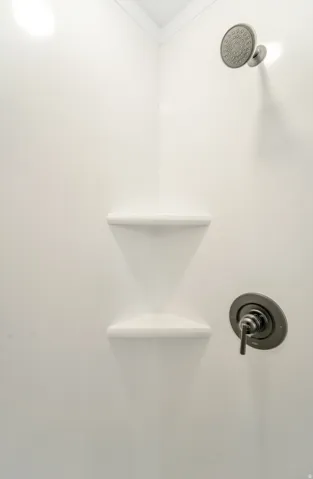 Photos are of a previously built home of the same floor plan. Finishes, colors, features, and upgrades may vary. White shower enclosure featuring a dark bronze shower head and control, complemented by two integrated corner shelves