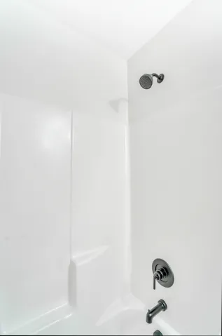 Photos are of a previously built home of the same floor plan. Finishes, colors, features, and upgrades may vary. White shower and tub combination featuring matte black fixtures, including a shower head, temperature control, and tub spout
