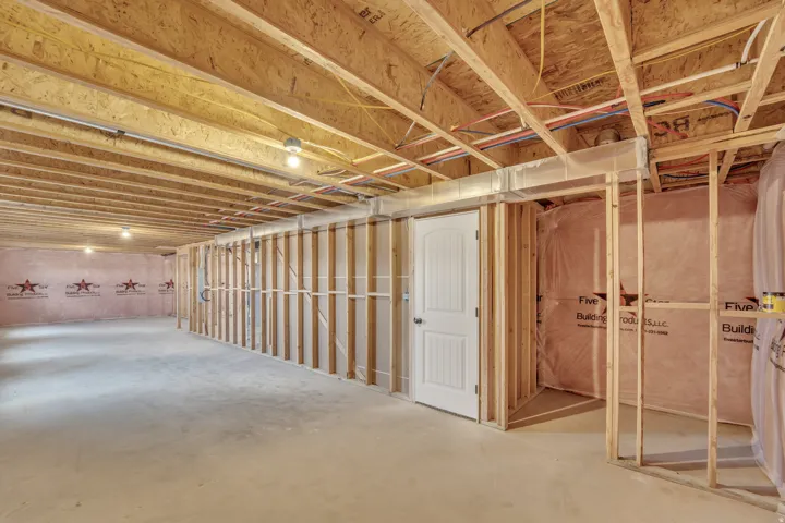 Photos are of a previously built home of the same floor plan. Finishes, colors, features, and upgrades may vary. Unfinished basement offering substantial customization potential, featuring exposed ceiling joists, framed walls, and an insulated perimeter