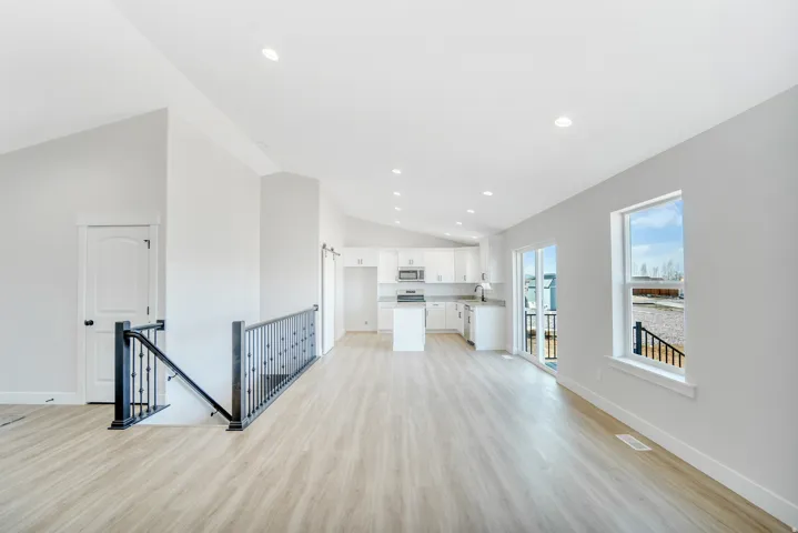 Photos are of a previously built home of the same floor plan. Finishes, colors, features, and upgrades may vary. Open-concept living area featuring vaulted ceilings, recessed lighting, and wood-finish flooring