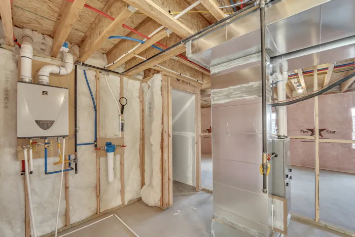 Photos are of a previously built home of the same floor plan. Finishes, colors, features, and upgrades may vary. Unfinished basement showcasing exposed wood joists, comprehensive ductwork, a tankless water heater, and a water filtration system