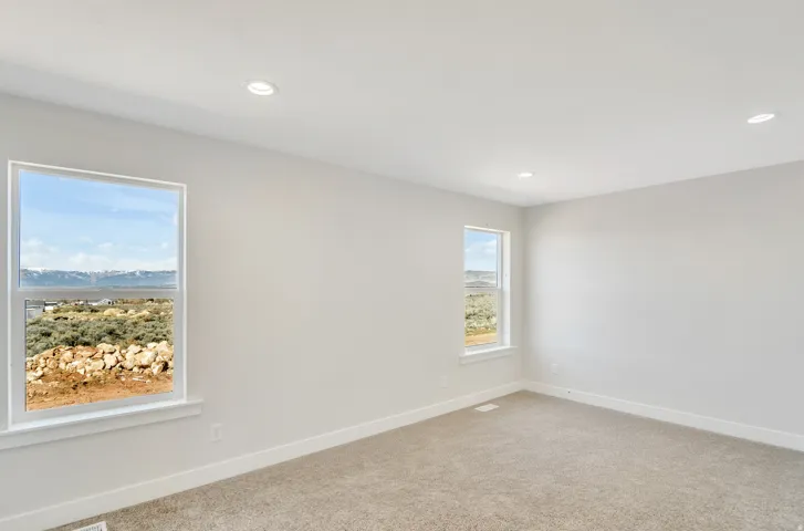Photos are of a previously built home of the same floor plan. Finishes, colors, features, and upgrades may vary. Expansive room featuring two windows with surrounding landscape, recessed lighting, neutral wall tones, and textured carpeting