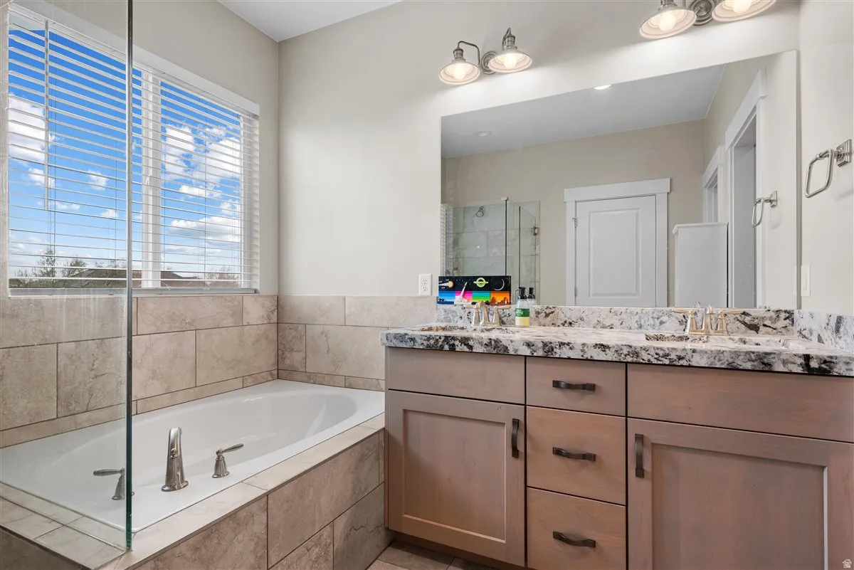 Bathroom featuring a built-in soaking tub with brushed nickel fixtures, surrounded by neutral-toned tile