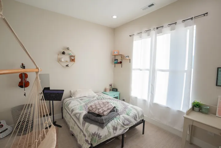 Bright room featuring neutral walls, recessed lighting, and a large window with white curtains