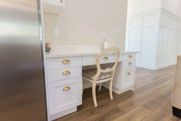 Built-in desk area featuring white cabinetry, gold-toned cup pulls, and a light-toned countertop