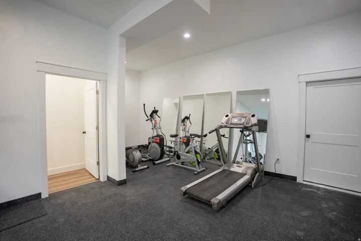 Dedicated fitness area featuring durable rubber flooring, recessed lighting, and a white interior door