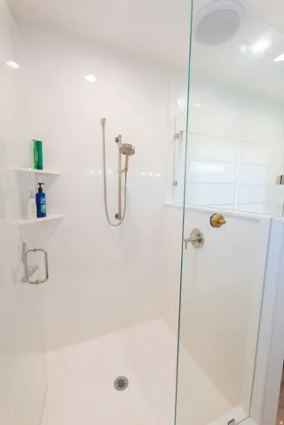 Contemporary shower with a glass enclosure, white paneled walls, and a recessed ceiling light