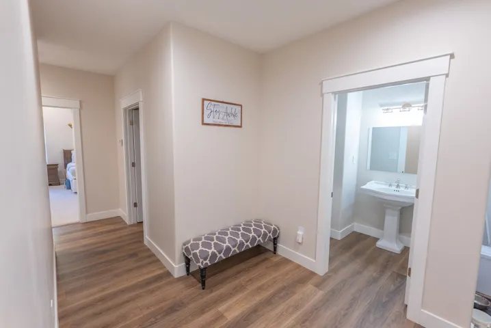 Hallway featuring wood-finish flooring, light neutral wall paint, and white trim