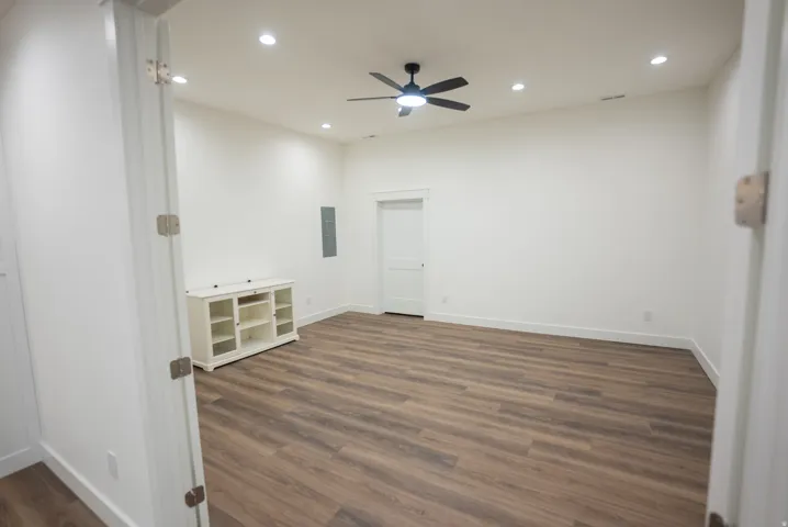 Spacious room featuring wood-finish flooring, recessed lighting, a ceiling fan, and white baseboards