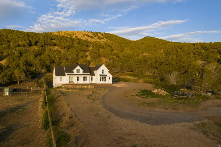 White farmhouse-style residence with dark shingle roofing and dormer windows