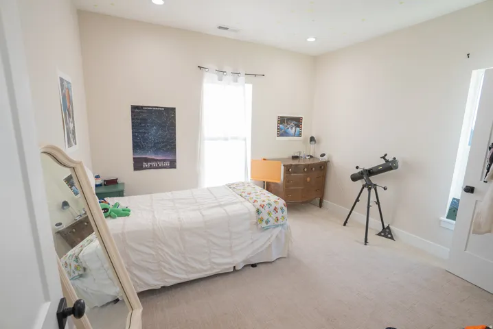 Neutral-toned bedroom featuring recessed lighting, a single window with white trim, and light-colored carpeting