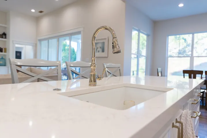 Kitchen island featuring an undermount sink, a polished nickel pull-down faucet, and a light-toned countertop