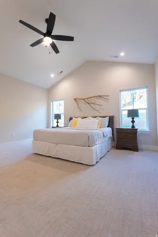 Vaulted ceiling bedroom featuring carpeting, recessed lighting, a ceiling fan, and two windows