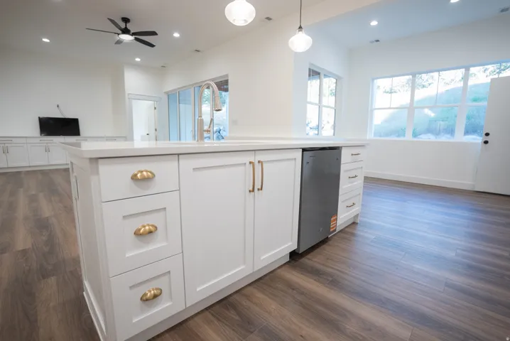 Kitchen island featuring white cabinetry, gold-tone hardware, and a stainless steel dishwasher