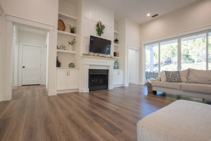 Expansive living area featuring wood-finish flooring, a built-in electric fireplace with mantel, custom shelving and cabinetry, and a large sliding glass door