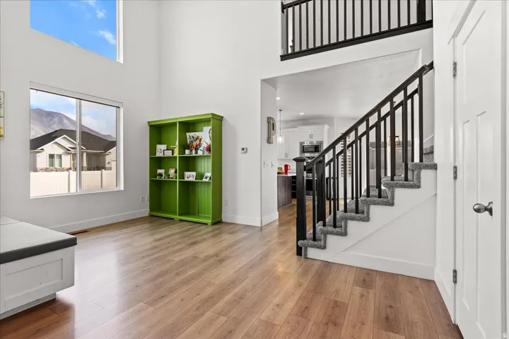 Two-story living area featuring wood-finish flooring, a contemporary staircase with dark balusters, a large picture window, and a transom window above