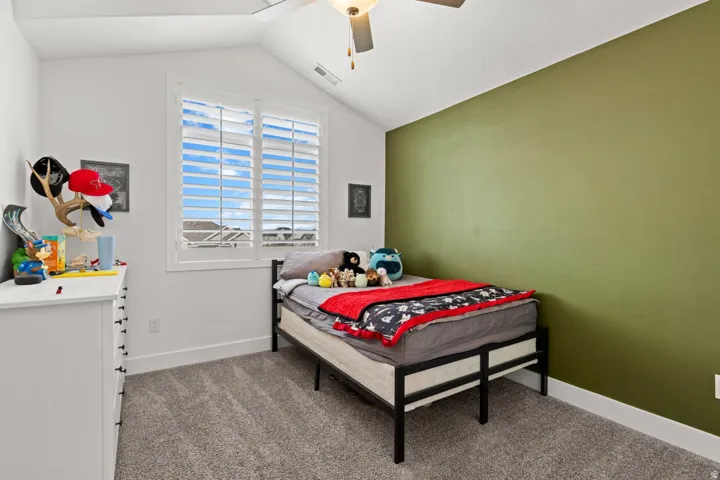 Room featuring an accent wall, plush carpet, and vaulted ceiling