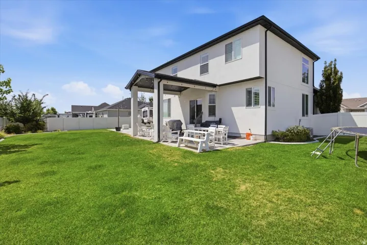 Expansive backyard featuring a manicured lawn, a covered patio, and a privacy fence