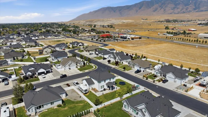 Aerial view of a new residential community featuring modern homes with clean architectural lines, dark asphalt roofing, manicured landscaping, and wide paved streets