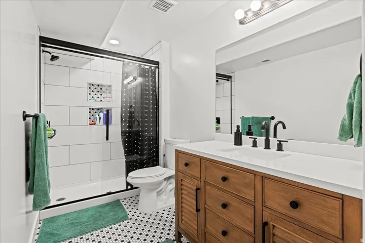 Bathroom featuring a wood-finish double vanity with a white countertop and matte black hardware