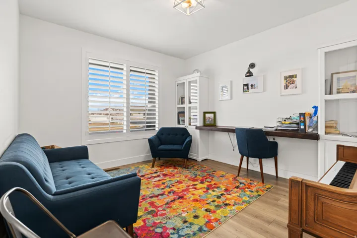 Bright room featuring white plantation shutters, a wood-finish flooring, and a built-in desk with a dark wood surface