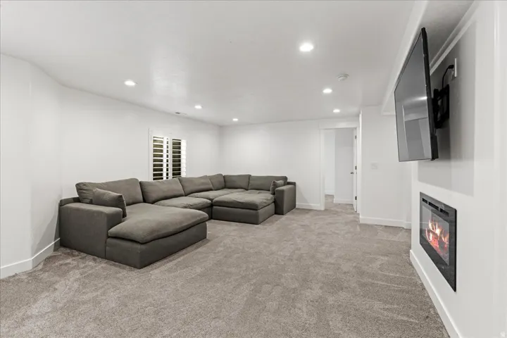 Spacious room featuring neutral carpeting, recessed lighting, and white plantation shutters