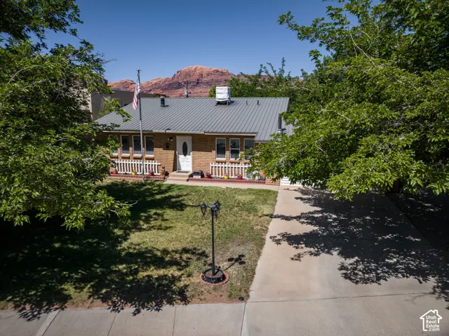 Brick exterior residence with a gray metal roof, featuring a white picket fence on the front porch